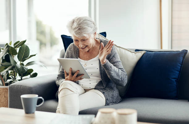 Ältere Frau mit Tablet auf Sofa.